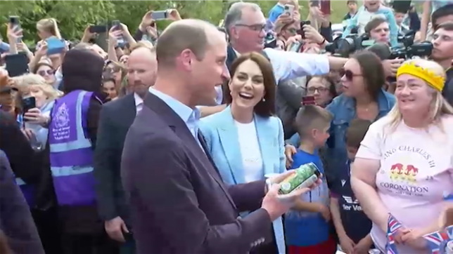 Le prince de Galles reçoit une boisson des fans devant Windsor.
