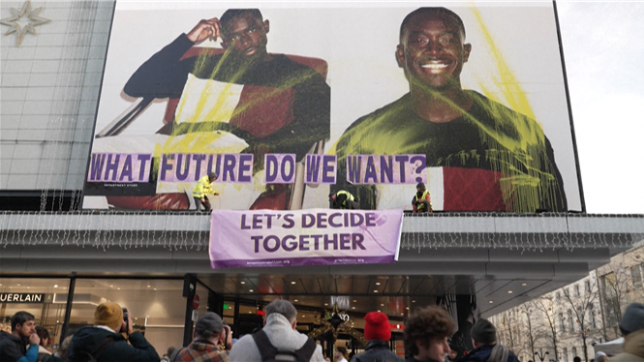 Des militants collent des messages et déploient des banderoles sur une affiche publicitaire géante qu'ils ont tagués dans le centre de Bruxelles pour dénoncer l'impact du Black Friday et de la surconsommation sur l'environnement et la société.