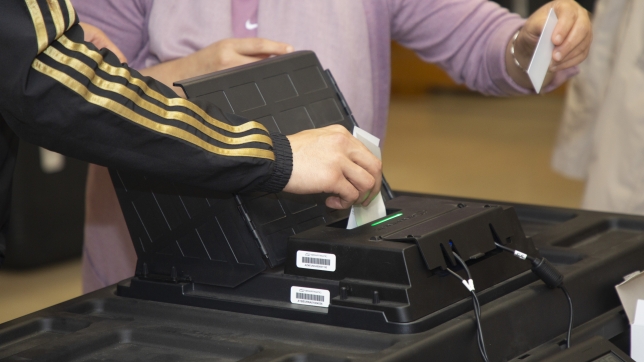 Un homme met le bulletin imprimé de son vote électronique dans l’urne alors qu’il vote dans un bureau de vote à Koekelberg, Bruxelles, dimanche 26 mai 2019.