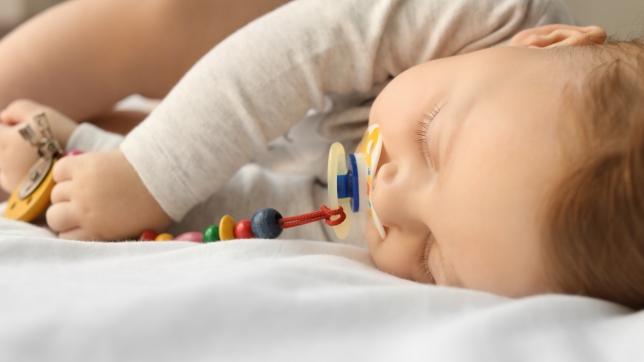 Image d’illustration d’un bébé qui dort avec un attache-tétine.