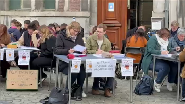 Pendant un arrêt de travail, les enseignants du Collège Saint-Barthélemy de Liège ont corrigé les devoirs de leurs élèves sur le trottoir. Ils souhaitent mettre la lumière sur leur travail de l’ombre.