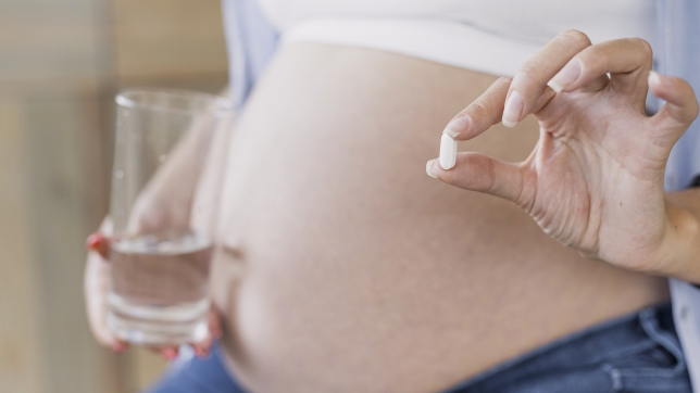 vue-de-cote-femme-enceinte-tenant-pilule.jpg