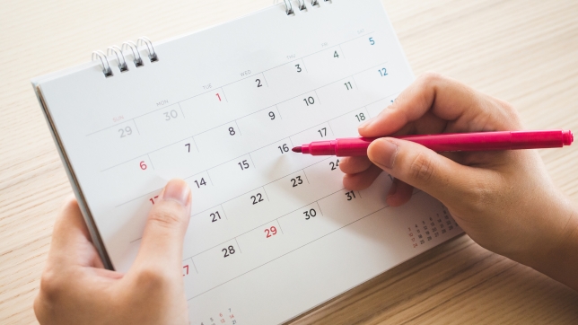 Hand with pen writing on calendar page closeup