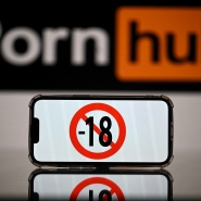 This photograph taken on May 24, 2022 in Toulouse shows screens displaying a minor child sign and the logo of the pornographic site Pornhub. The judicial examination of Arcom request against porn sites has been postponed to one month, on May 24, 2022. Arcom media regulator requests five pornographic sites to be blocked as they are not preventing the exposure of minors to their content, and French telecom operators to block access to the pornographic sites. (Photo by Lionel BONAVENTURE / AFP)