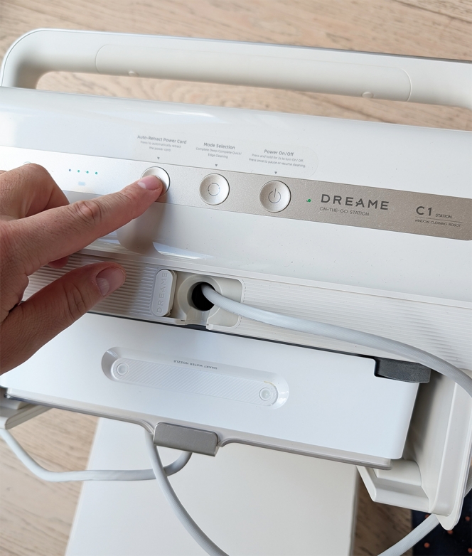 Le bouton pour l’enroulage automatique du cordon d’alimentation, après un nettoyage. Le robot se range à la verticale.